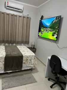 马瑙斯Casa com suite bem localizada的一间卧室，墙上有一张床和一台电视