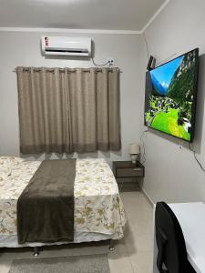 马瑙斯Casa com suite bem localizada的一间卧室，里面有一张床和一台平板电视