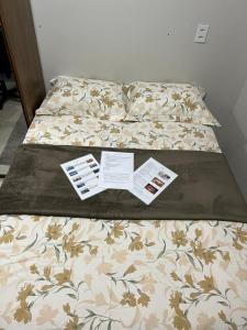 马瑙斯Casa com suite bem localizada的一张床，上面有一张被子，还有两本小册子 更多26张照片