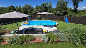 a swimming pool with two umbrellas and chairs and a pool at Villa Aurora in Hrebinec