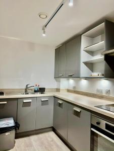 una cocina con armarios de acero inoxidable y fregadero en Digbeth Place - Birmingham City Centre, en Birmingham