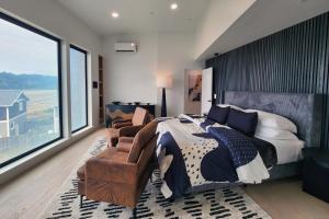 a bedroom with a large bed and a chair at Spectacular Bridge and Bay Views! Bay's Edge! in Waldport +23 photos
