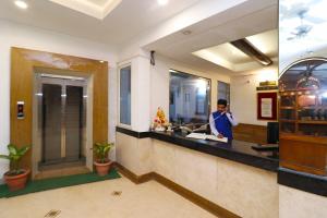 un hombre parado en un mostrador en una habitación de hotel en Hotel O Highway Inn International, en Dhulagari
