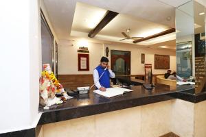 un hombre parado en un mostrador hablando por teléfono en Hotel O Highway Inn International, en Dhulagari