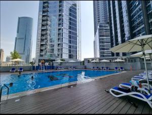 a swimming pool with chairs and umbrellas in a city at Cozy Room In Abu Dhabi Reem island Near to Galeria Mall in Abu Dhabi