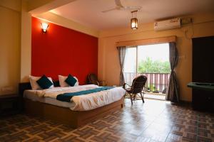 een slaapkamer met een bed met een rode muur bij Hotel Anandam Elegance in Morjim +20 foto's