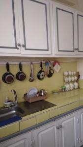 a kitchen with white cabinets and utensils on the wall at Ravissante appartement dans les jardins in Oulad Akkou