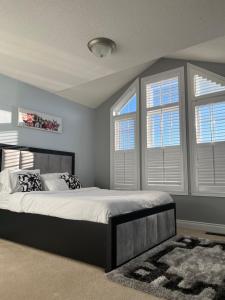 a bedroom with a large bed and two windows at 3300 SqFt - Modern and Comfort - 3 BDRM Getaway - Relax - Unwind - Explore - Near Toronto Pearson Airport & Toronto Downtown in Brampton