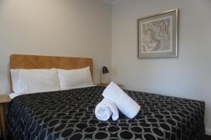 a hotel room with a bed with a pillow on it at Wagga Gardens Motel in Wagga Wagga