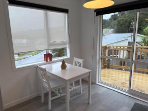 a white table and chairs in a room with windows at Charming Home in Lower Hutt