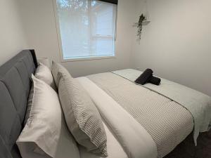 una camera da letto con un letto con cuscini e una finestra di Charming Home a Lower Hutt