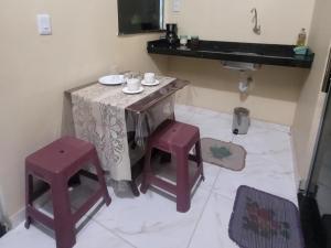 a bathroom with a table and two stools and a sink at Suíte Aconchego Soure in Soure