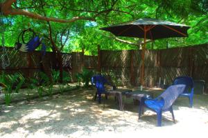 three blue chairs and a table with an umbrella at MANGO BREEZE Casa de Playa en Tierrabomba in Tierra Bomba