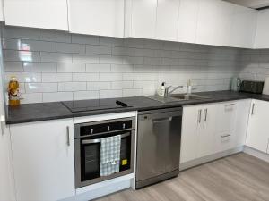 a kitchen with white cabinets and a sink and a dishwasher at Space, Style and Serenity in Lower Hutt