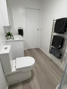 a white bathroom with a toilet and a sink at Space, Style and Serenity in Lower Hutt