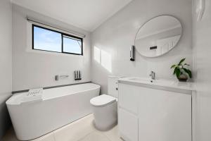 a white bathroom with a tub and a sink and a mirror at Tenby Point Waterfront Views & Tranquil Garden in Queensferry +36 photos