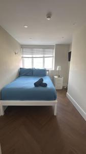 une chambre avec un lit avec des draps bleus et une fenêtre dans l'établissement 30C The Luxury Studios near Arsenal and Central London, à Londres