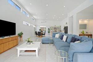 a living room with a blue couch and a tv at Ocean Breeze on Malibu in Kingscliff