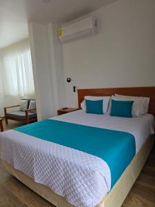 a bedroom with a large bed with blue and white sheets at CASA GALAPAGOS by Hostal Fragata in Puerto Ayora
