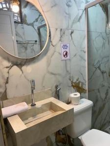 a bathroom with a sink with a toilet and a mirror at Suite Tarituba 2 in Angra dos Reis
