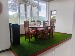 a dining room with a table and chairs on a green rug at Minindu village in Badulla