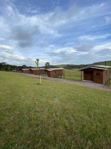eine Reihe von Gebäuden auf einem Feld mit Grasfläche in der Unterkunft Chalé Campos Da Serra in São José dos Ausentes + 47 Fotos