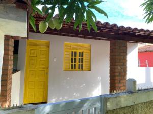 deux portes jaunes sur le côté d'une maison dans l'établissement Casa Amarela em Cacha Pregos, à Vera Cruz de Itaparica 2 autres photos