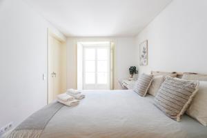 a white bedroom with a large bed with towels on it at Suite in Cozy Apartment in Chiado in Shared House in Lisbon
