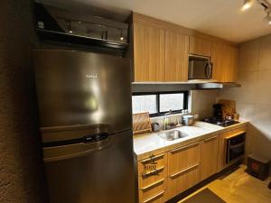 a stainless steel refrigerator in a kitchen with wooden cabinets at Milagres - VIllas Patacho in Pôrto de Pedras