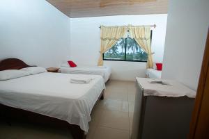 une chambre avec deux lits et une fenêtre dans l'établissement Hostal casa de los delfines, à Puerto Villamil 4 autres photos