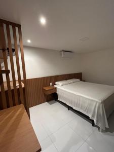 Un pequeño dormitorio con una cama y una mesa. en Cobertura pé na areia, 3 suítes e área externa, en Ilhéus