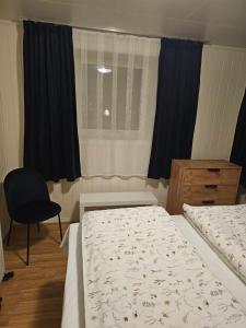 a bedroom with two beds and a chair and a window at Apartment at Lofoten. Mølnarodden. in Sund +14 photos