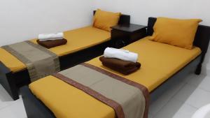 three beds in a room with yellow and brown at Homestay Legundi Syariah in Tanjungkarang