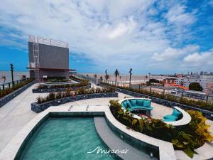 ein Schwimmbad neben einem Strand und einem Gebäude in der Unterkunft Garden Haus Beira-Mar, Jardim Oceania-Miramar Hospedagens in Tambaú