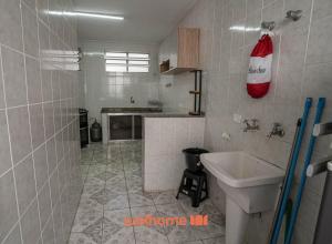 a white tiled bathroom with a sink and a counter at Apartamento Peruibe Beira Mar Perto do Centro in Peruíbe