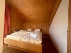 a bed in a room with a wooden ceiling at Spatzennest in Hohentauern