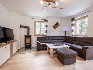 a living room with a leather couch and a tv at Ebersberger in Donnersbachwald