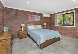 Un dormitorio con una cama y una pared de ladrillo. en Morning Glow - Wake up to breathtaking views and golden sunrises at this serene coastal retreat., en Bombo