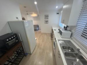 a small kitchen with a refrigerator and a sink at Birkdale Granny Flat in Birkdale