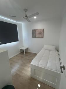 a white bedroom with a bed and a flat screen tv at Birkdale Granny Flat in Birkdale