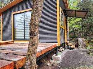 a house with a wooden deck next to a tree at Cabañas Del Monte 2 in Melipeuco