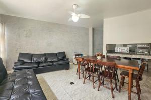 a living room with a black leather couch and a table at 11A - Apto c/2 QUARTOS, Sala e Cozinha completa,1WC, 1 Vaga, Roupa de Cama e VIVO FIBRA in Guarujá