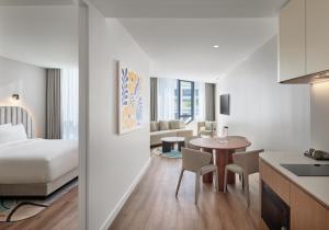 a hotel room with a bed and a table and chairs at Hyatt House South Melbourne in Melbourne +41 photos