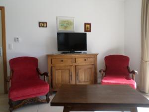 salon z 2 czerwonymi krzesłami i telewizorem w obiekcie Gremin w mieście Somme-Leuze