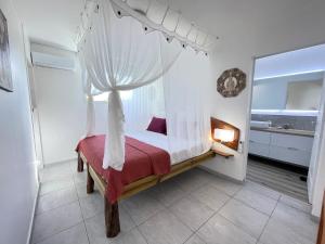 a bedroom with a canopy bed with a window at Tibo bas de villa NEUF accès mer in Deshaies