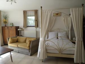 1 dormitorio con cama con dosel y sofá en Gremin, en Somme-Leuze