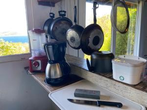 a kitchen counter with pots and pans on a window at Bangalô Pontal do Atalaia com piscina para casal ou família in Arraial do Cabo