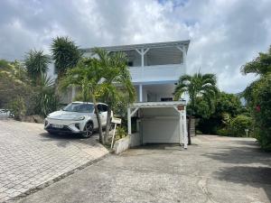 a white car parked in front of a house at Tibo bas de villa NEUF accès mer in Deshaies