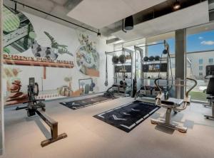 a gym with several tread machines and a wall with a mural at Boulevard Stays Downtown Highrise STU Sky Pool Parking Gym 05 in Phoenix