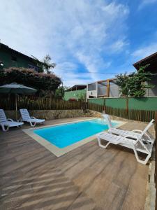 a swimming pool with two lounge chairs next to a fence at Flat rústico e aconchegante próximo a Paraty e Trindade in Paraty